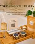 A wooden bath tray set in a spa-like bathroom scene with a glass of white wine, a candle, two wrapped bath bombs, two silver containers with body oil and body mist, a pouch of bath salts, and a card reading 'Your Guided Somatic Meditation.' Large text at the top says 'YOUR SEASONAL RESET' and lists included items: bath bombs, body oil, body mist, candle, and guided somatic meditation. Subscription box Canada.